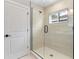 Elegant shower with frameless glass enclosure and beige tile surround, and a black shower head and door handle at 1809 Simonton Ave, Orlando, FL 32806