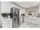 Well-lit kitchen with stainless steel refrigerator, white cabinets, and a farmhouse sink offering modern elegance at 207 Pembrook Pl, Longwood, FL 32779