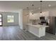 Modern kitchen with a quartz countertop island, stainless steel appliances, pendant lighting and gray-tone wood flooring at 2293 Sw 178Th Lane Rd, Ocala, FL 34473