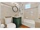 Cozy bathroom with a green vanity, a round mirror, and a shower with a floral curtain at 234 N Lakeview Ave, Winter Garden, FL 34787