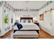 Elegant main bedroom with a large bed, bench, and patterned accent wallpaper above white paneling at 234 N Lakeview Ave, Winter Garden, FL 34787