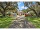 Stately brick home with white columns, gated entrance, and mature trees lining the driveway creating a picturesque view at 2525 Cr 543, Sumterville, FL 33585