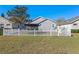 A spacious backyard featuring a white picket fence, enclosed by a black iron fence on the side at 300 Stonington Way, Deland, FL 32724