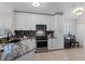 Modern kitchen with white cabinets, granite countertops, and stainless steel appliances at 300 Stonington Way, Deland, FL 32724