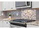 Close-up of the kitchen's gas range with stainless steel appliances and tile backsplash at 300 Stonington Way, Deland, FL 32724