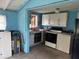 A view of the kitchen with blue walls and white cabinets. There is a range and a washer at 3420 Avenue R Nw, Winter Haven, FL 33881