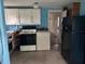 A blue kitchen features white cabinets, black refrigerator, and vintage white washer and dryer at 3420 Avenue R Nw, Winter Haven, FL 33881