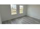 Bright bedroom with wood-look flooring, neutral walls, and two large windows at 4875 Sw 159Th Lane Rd, Ocala, FL 34473