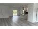 Bright, open floor plan with gray wood flooring connecting living area to kitchen, filled with natural light at 4875 Sw 159Th Lane Rd, Ocala, FL 34473