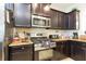 Well-equipped kitchen featuring stainless steel appliances, dark wood cabinetry, and granite countertops at 5384 Oakbourne Ave, Davenport, FL 33837