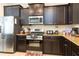 Well-equipped kitchen featuring stainless steel appliances, dark wood cabinetry, and granite countertops at 5384 Oakbourne Ave, Davenport, FL 33837