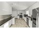 Modern kitchen featuring stainless steel appliances, white cabinetry, and dark countertops with wood-look flooring at 662 Sausalito Blvd, Casselberry, FL 32707