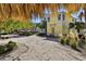 Exterior view of a yellow two-story home with a sandy yard, palm trees, and outdoor seating at 8005 Flip Flop Way, Kissimmee, FL 34747