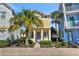 Charming yellow two-story home with blue trim, a well-manicured lawn, and vibrant tropical landscaping at 8005 Flip Flop Way, Kissimmee, FL 34747