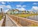 Scenic view of colorful townhomes on the water, featuring a wood bridge and green grass at 8005 Flip Flop Way, Kissimmee, FL 34747