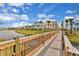 Scenic view of colorful townhomes on the water, featuring a wood bridge and green grass at 8005 Flip Flop Way, Kissimmee, FL 34747