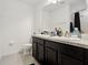 Functional bathroom equipped with double sinks, dark wood cabinetry, and tiled floor at 841 Benjamin Trl, Davenport, FL 33837