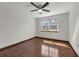 This clean bedroom features a ceiling fan, wood floor, bright window, and white walls at 9332 Windy Ridge Rd, Windermere, FL 34786