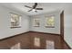 Bright bedroom featuring hardwood floors, a ceiling fan, and three large windows at 9332 Windy Ridge Rd, Windermere, FL 34786