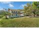 Charming two-story home features a full wrap-around porch, lush lawn, and mature shade trees at 9332 Windy Ridge Rd, Windermere, FL 34786