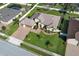 Aerial view of a light yellow house and paver driveway with manicured lawn in a residential neighborhood at 9716 Royal Vista Ave, Clermont, FL 34711