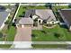 Aerial view of a light yellow house with a paver driveway and manicured lawn in a residential neighborhood at 9716 Royal Vista Ave, Clermont, FL 34711