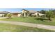 Well-manicured lawn with various palm trees and plantings accentuate the front of this light yellow home at 9716 Royal Vista Ave, Clermont, FL 34711