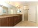 Bathroom with a double sink vanity featuring granite counters, wooden cabinets, and glass shower at 9716 Royal Vista Ave, Clermont, FL 34711