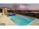Inviting pool and hot tub area with outdoor dining and lounge seating overlooking a tranquil lake at twilight with fireworks at 14544 Avenue Of The Rushes, Winter Garden, FL 34787