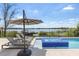 Relaxing lakeside pool area featuring lounge chairs, a large umbrella, and an in-ground jacuzzi at 14544 Avenue Of The Rushes, Winter Garden, FL 34787