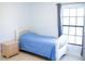 Inviting bedroom featuring a cozy bed with blue sheets, complemented by a matching bedside table and a bright window at 14712 Eagles Crossing Dr, Orlando, FL 32837