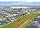 Aerial shot shows a suburban neighborhood with similar houses, green spaces, and a distant lake view at 17052 Cercis Loop, Clermont, FL 34711