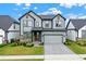 Two-story home boasts a modern exterior with gray siding, stone accents, and a well-manicured front lawn at 17052 Cercis Loop, Clermont, FL 34711