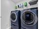 Modern laundry room showcasing blue front load washer and dryer with wire rack shelf above at 17052 Cercis Loop, Clermont, FL 34711
