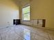 Damaged bedroom features tile flooring, a window with natural light, and yellow walls awaiting renovation at 235 Tuscany Pointe Ave, Orlando, FL 32807