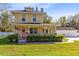 Charming two-story yellow home featuring a welcoming front porch, American flag, and well-manicured landscaping at 2431 Narcissus Ave, Sanford, FL 32771