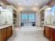 Luxurious bathroom with a large soaking tub beneath a window, flanked by wood vanities and open shelving at 254 Sylvan Blvd, Winter Park, FL 32789