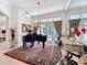 Elegant living area featuring a grand piano, chandelier, and French doors leading to an outdoor space at 254 Sylvan Blvd, Winter Park, FL 32789