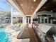 Outdoor kitchen and bar area featuring a grill, countertops, and seating next to a pool and patio at 254 Sylvan Blvd, Winter Park, FL 32789