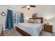 Cozy bedroom featuring a queen bed, a ceiling fan, and a large window with blue curtains at 2683 Manesty Ln, Kissimmee, FL 34747