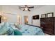 This comfortable bedroom features a ceiling fan, a dresser with television and a bed decorated with sea-themed linens at 2683 Manesty Ln, Kissimmee, FL 34747