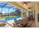 Covered patio with dining and lounge seating adjacent to the pool area at 2683 Manesty Ln, Kissimmee, FL 34747