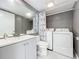 Bathroom with a mirror, white sink, a toilet, and a laundry setup with washer and dryer, all in a modern style at 5401 Elm Ct # 303, Orlando, FL 32811