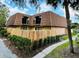 A charming townhome features a wood fence, mature landscaping, and a unique roof design at 5401 Elm Ct # 303, Orlando, FL 32811