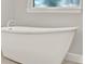 Bright bathroom featuring a modern white soaking tub beneath a window with crisp white trim at 5499 Orange Orchard Dr, Winter Garden, FL 34787