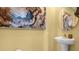 Stylish half bathroom with a pedestal sink, round mirror, and artistic wall decor at 994 Lido Dr, Howey In The Hills, FL 34737