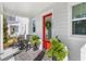 Inviting front porch with rocking chairs, potted plants, and a bright red door with decorative wreath and sidelight window at 1073 Sadler Oaks Way, Winter Garden, FL 34787