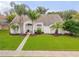 Charming single-story home featuring a well-manicured lawn, palm trees, and a welcoming front entrance at 1145 Lake Rogers Cir, Oviedo, FL 32765