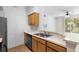 Open kitchen with wood cabinetry, stainless steel sink, and view to balcony at 13037 Mulberry Park Dr # 529, Orlando, FL 32821