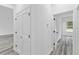 Hallway with gray wood-look flooring, white walls, and several doorways leading to other rooms at 13141 Sw 83Rd Ter, Ocala, FL 34473